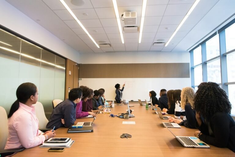 Board members around a conference table listening to a presentation