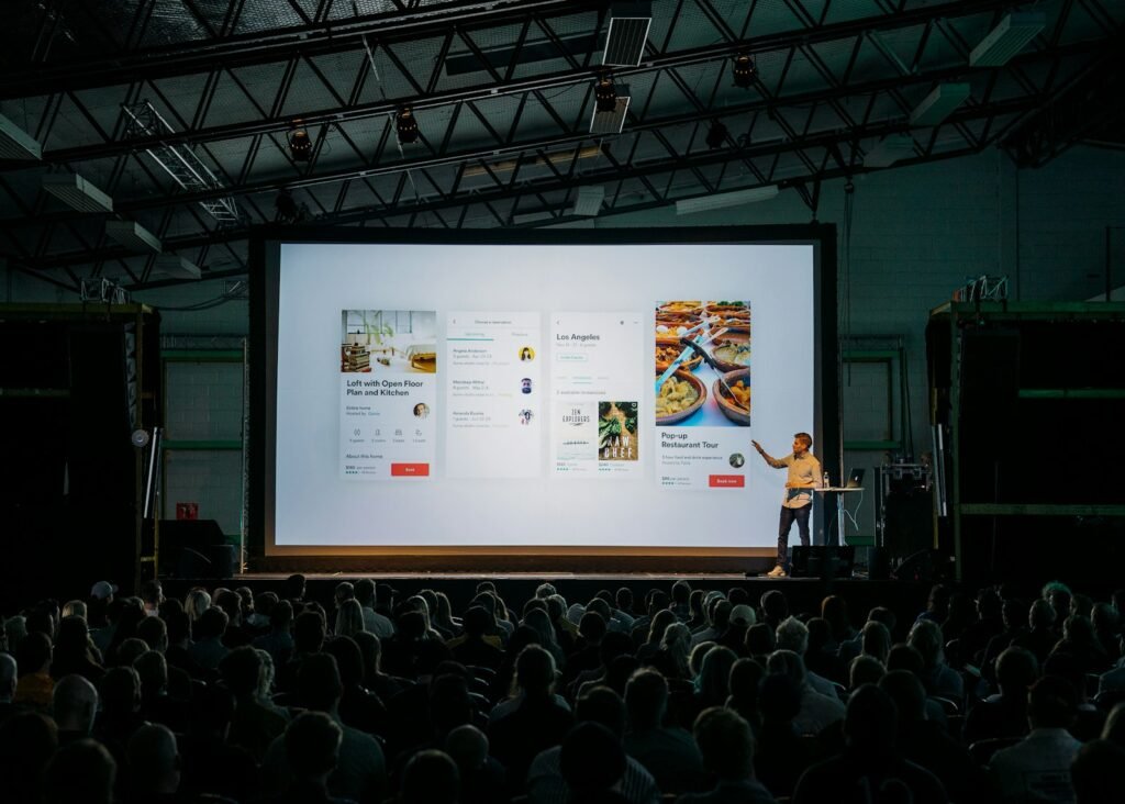 Speaker telling a story on stage in front of a presentation slide and audience