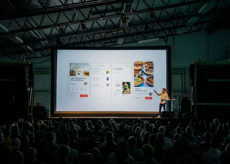 Speaker telling a story on stage in front of a presentation slide and audience