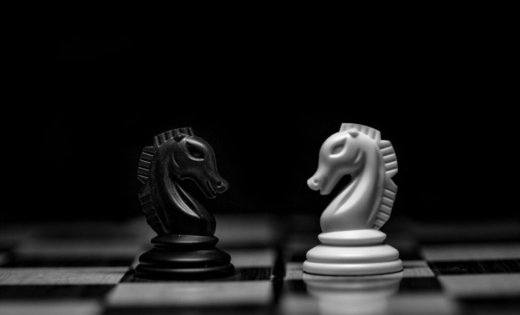 Black and white chess knights facing each other, representing competitive positioning